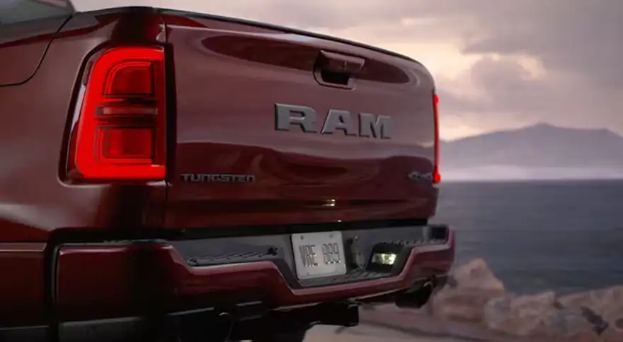 Rear view of a dark red RAM 1500 Tungsten with illuminated LED taillamps at dusk by the water