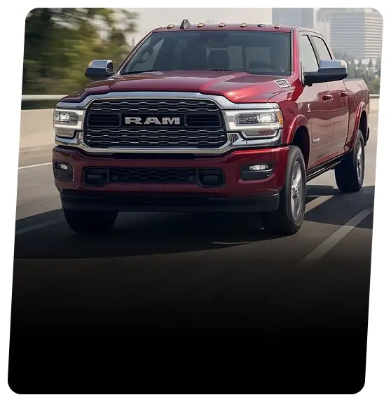 Red RAM heavy-duty pickup driving on a city highway