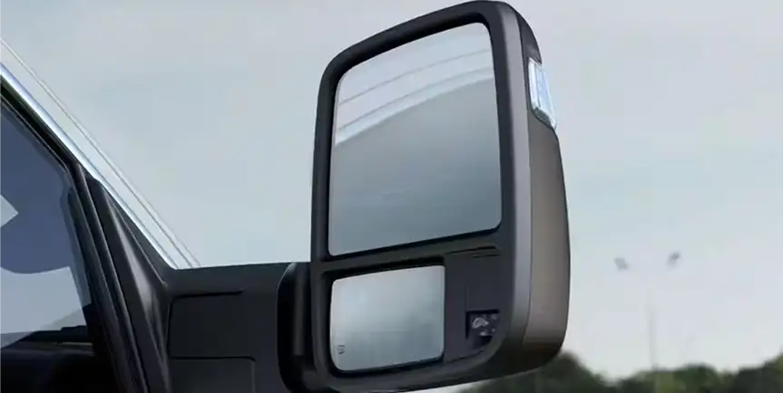 Extended telescopic trailer tow mirror on the side of a white RAM 1500