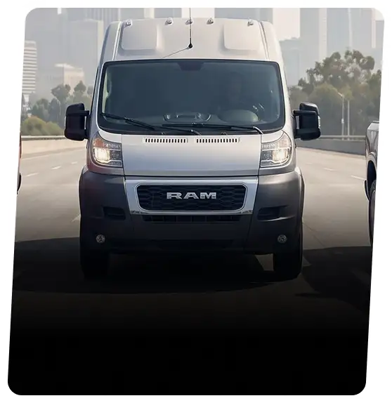 White RAM ProMaster high-roof cargo van driving through a city