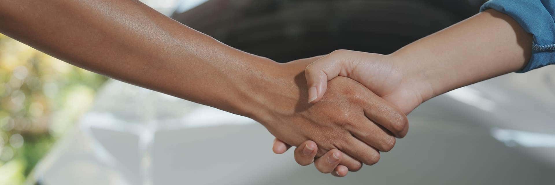 shaking hands in front of vehicle