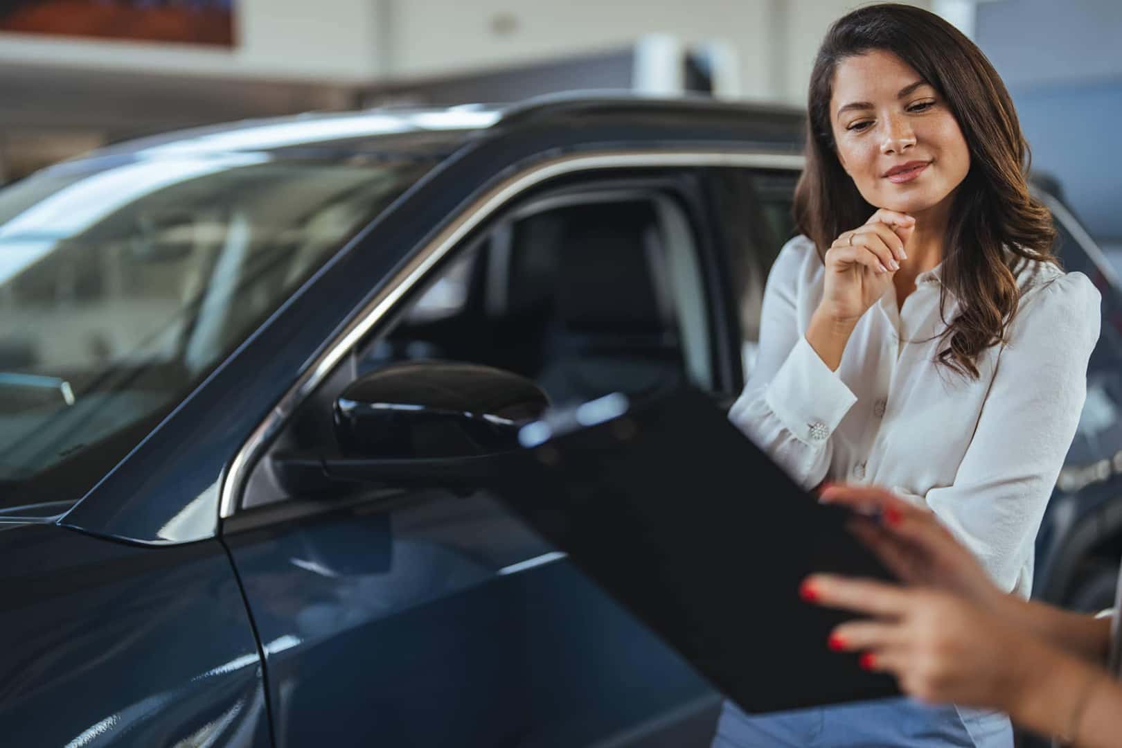 woman looking at paperwork at car dealership