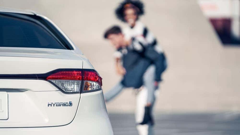 2020 Corolla Hybrid LE with happy couple in the background