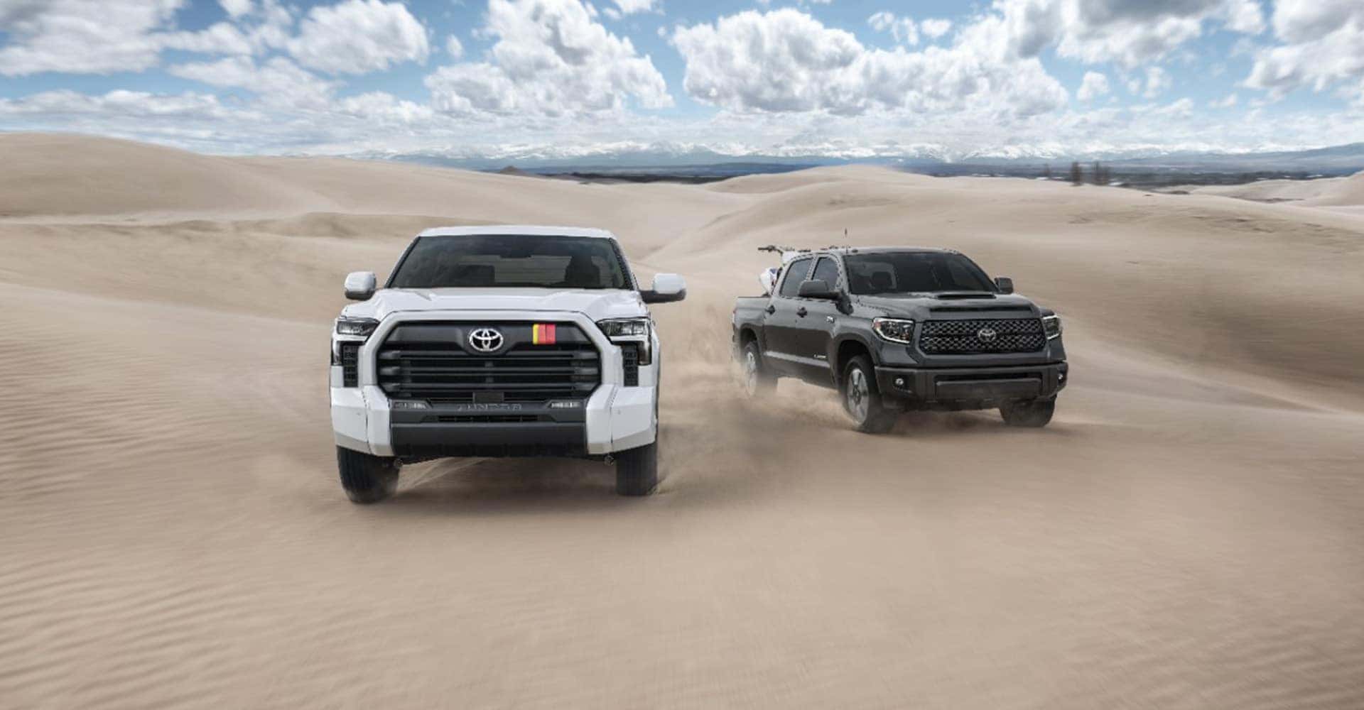 Two trucks driving on sand
