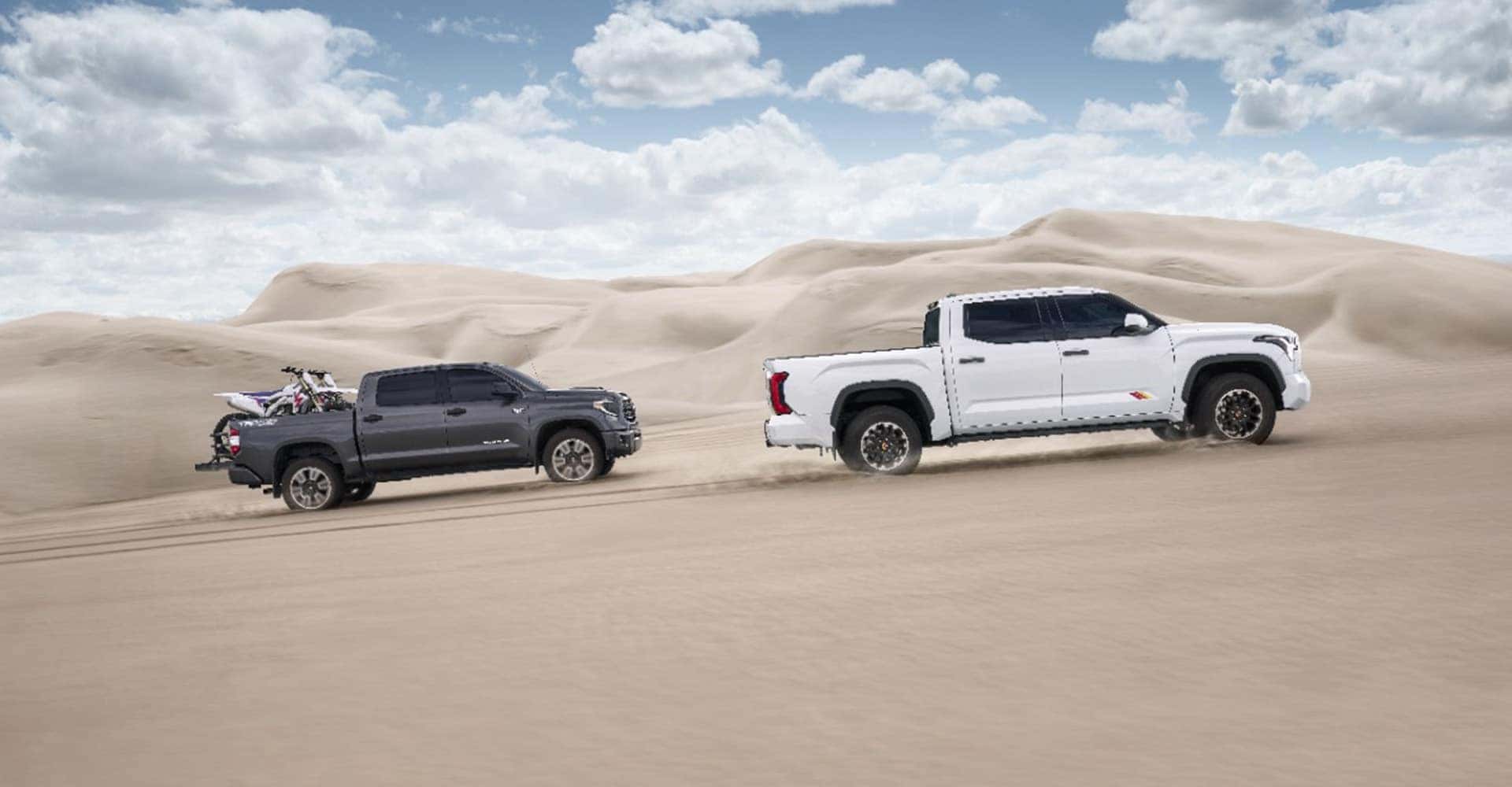 side of two trucks driving on sand