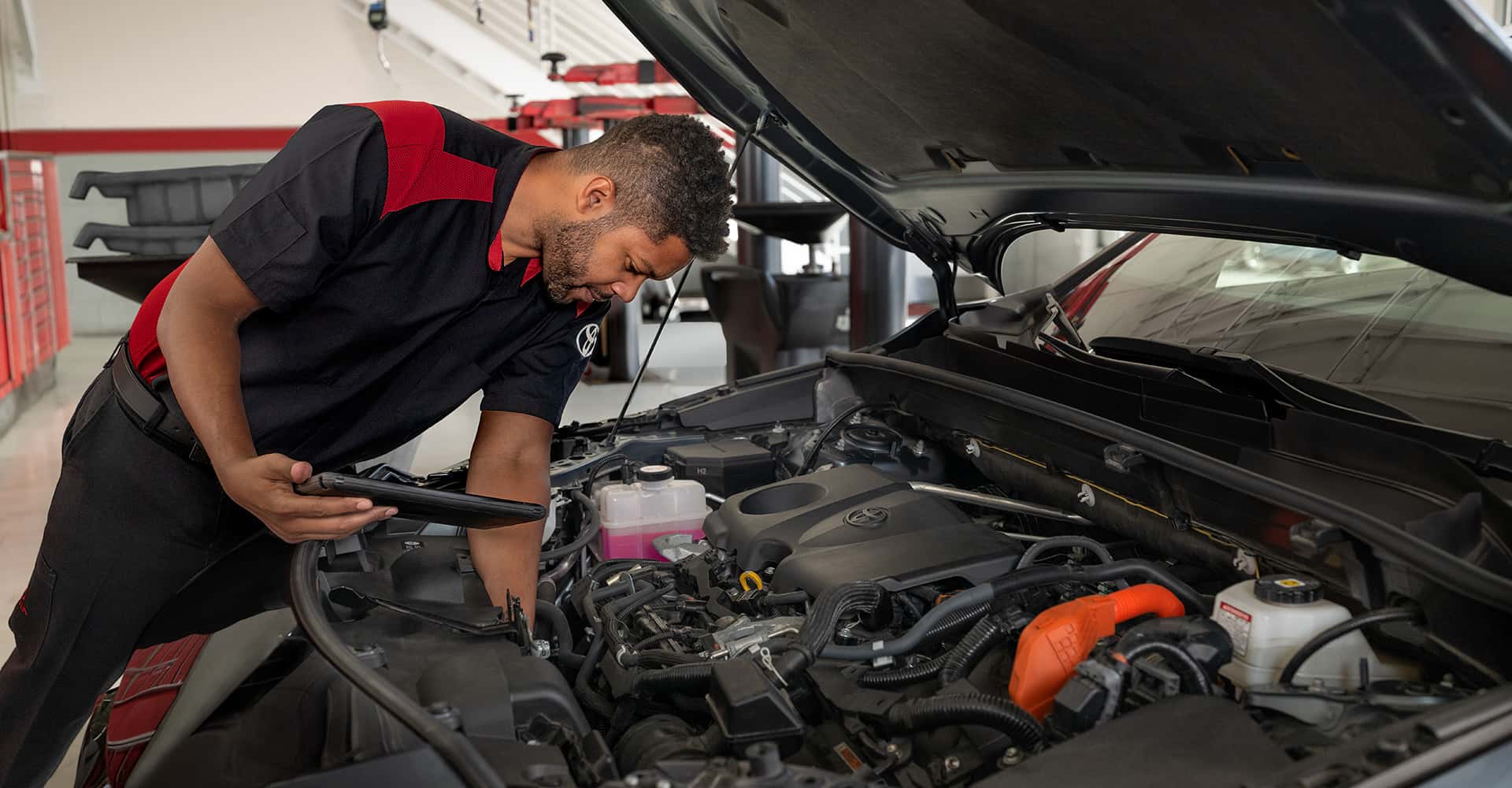 Toyota technician inspecting under hood of vehicle