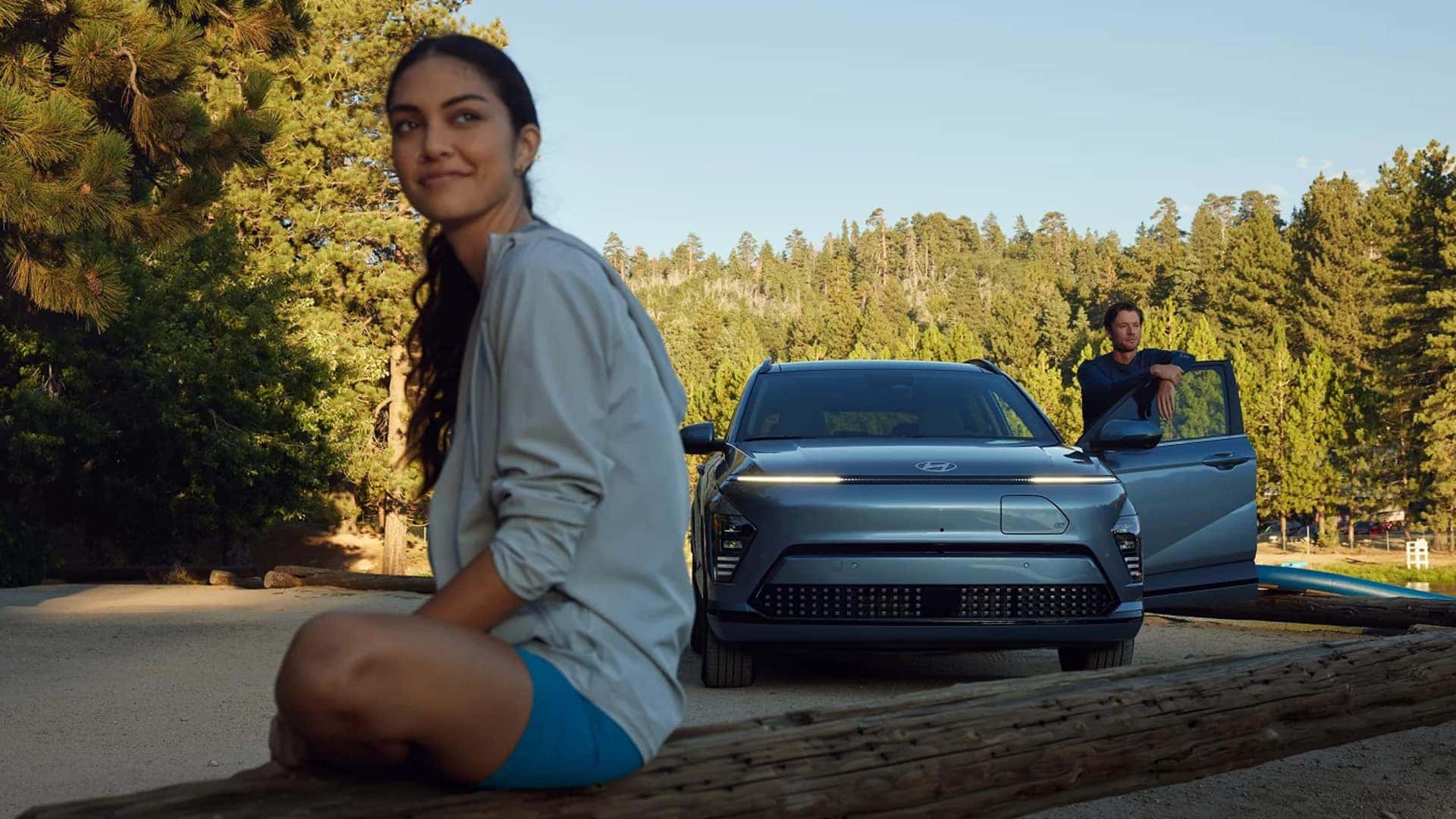 Woman Siting on Log in Front of 2025 Kona Electric