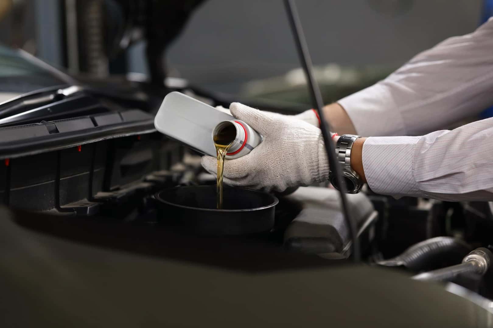 Difference between synthetic oil & conventional oil at Winner's Circle CDJR | Close up of mechanic's hands pouring oil into car engine